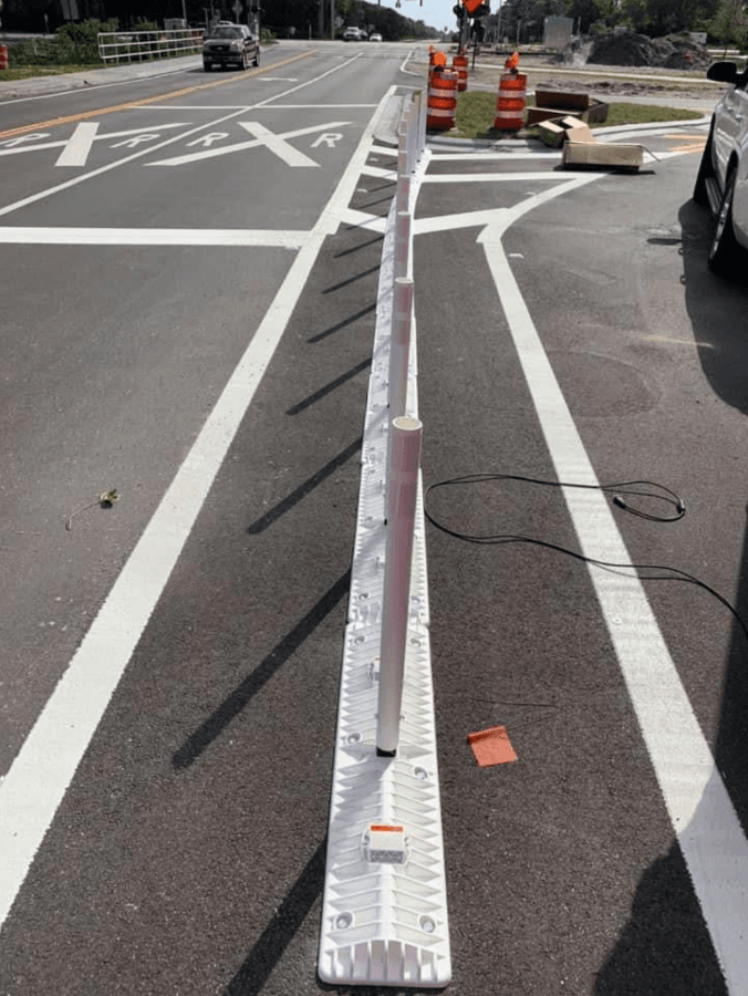 Lane-separator delineator being installed at a railroad crossing intersection with RXR pavement markings