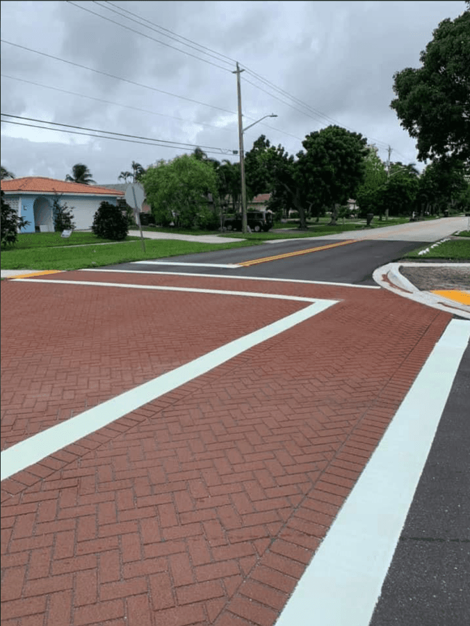 Decorative red brick crosswalk with crisp white striping framing the intersection
